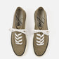 Green sneaker with white laces on a light beige background