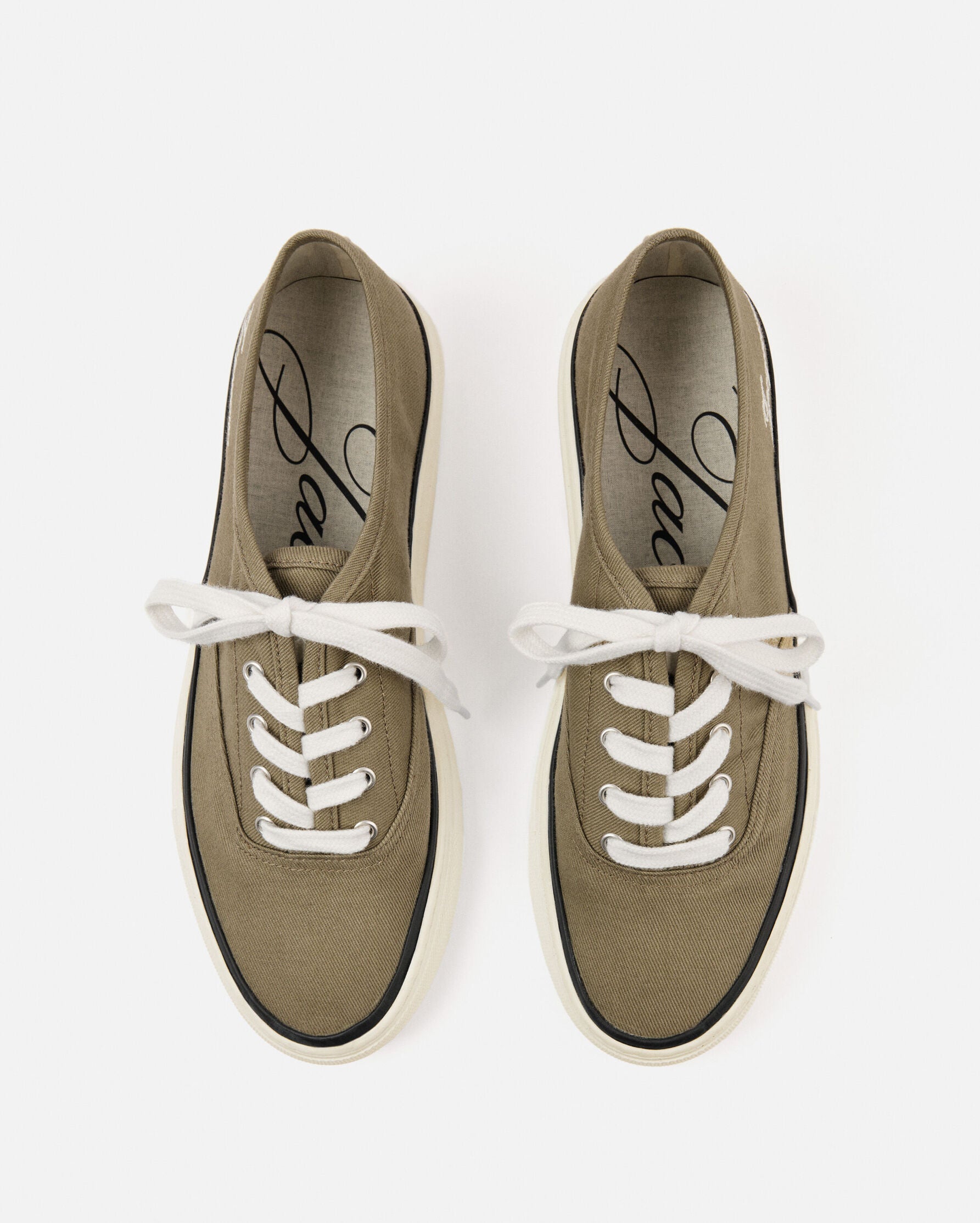 Green sneaker with white laces on a light beige background