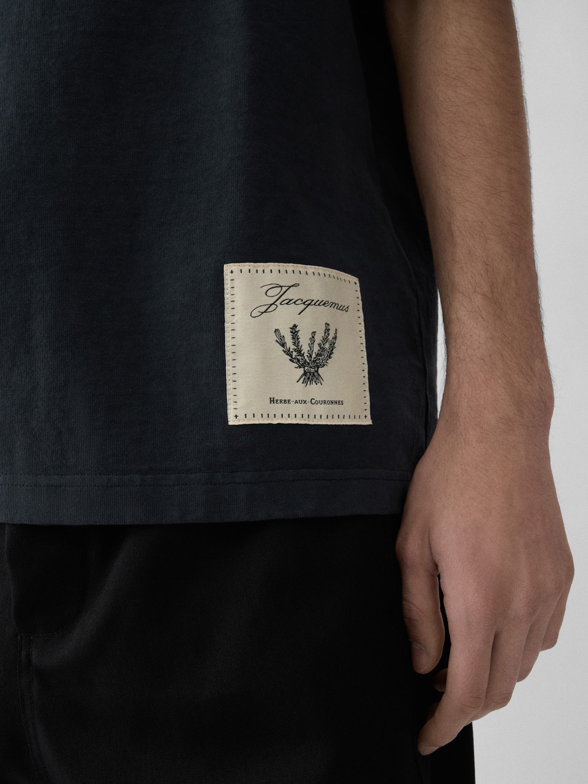 Navy t-shirt with a beige label on a light gray background JACQUEMUS
