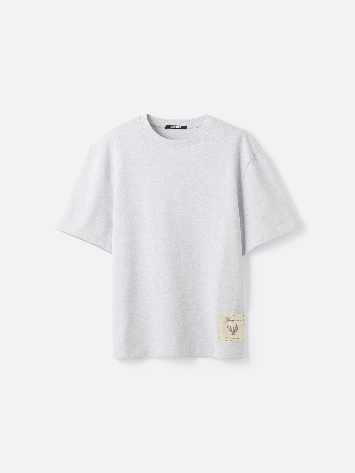 Grey t-shirt with a beige label on a light gray background JACQUEMUS