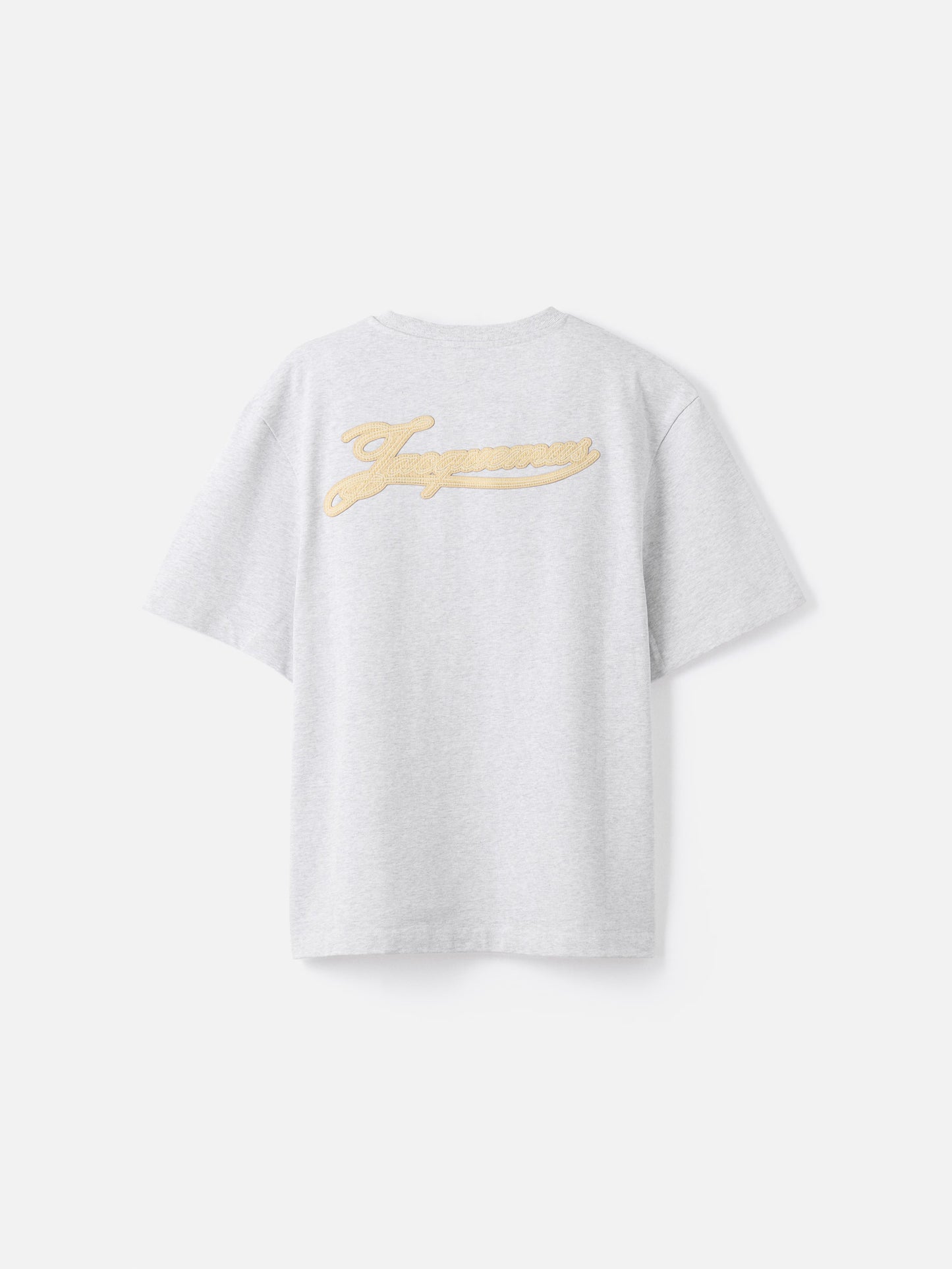 Grey t-shirt with a beige label on a light gray background JACQUEMUS