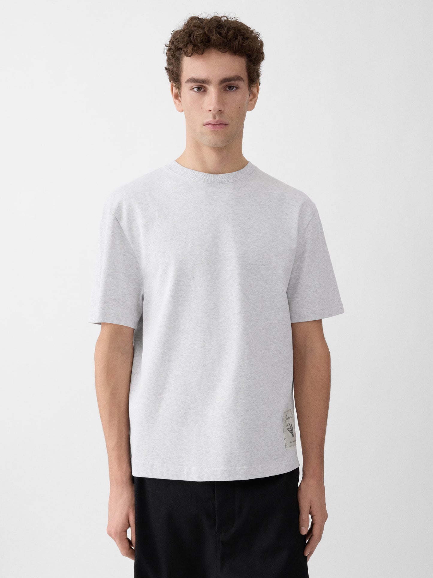 Grey t-shirt with a beige label on a light gray background JACQUEMUS