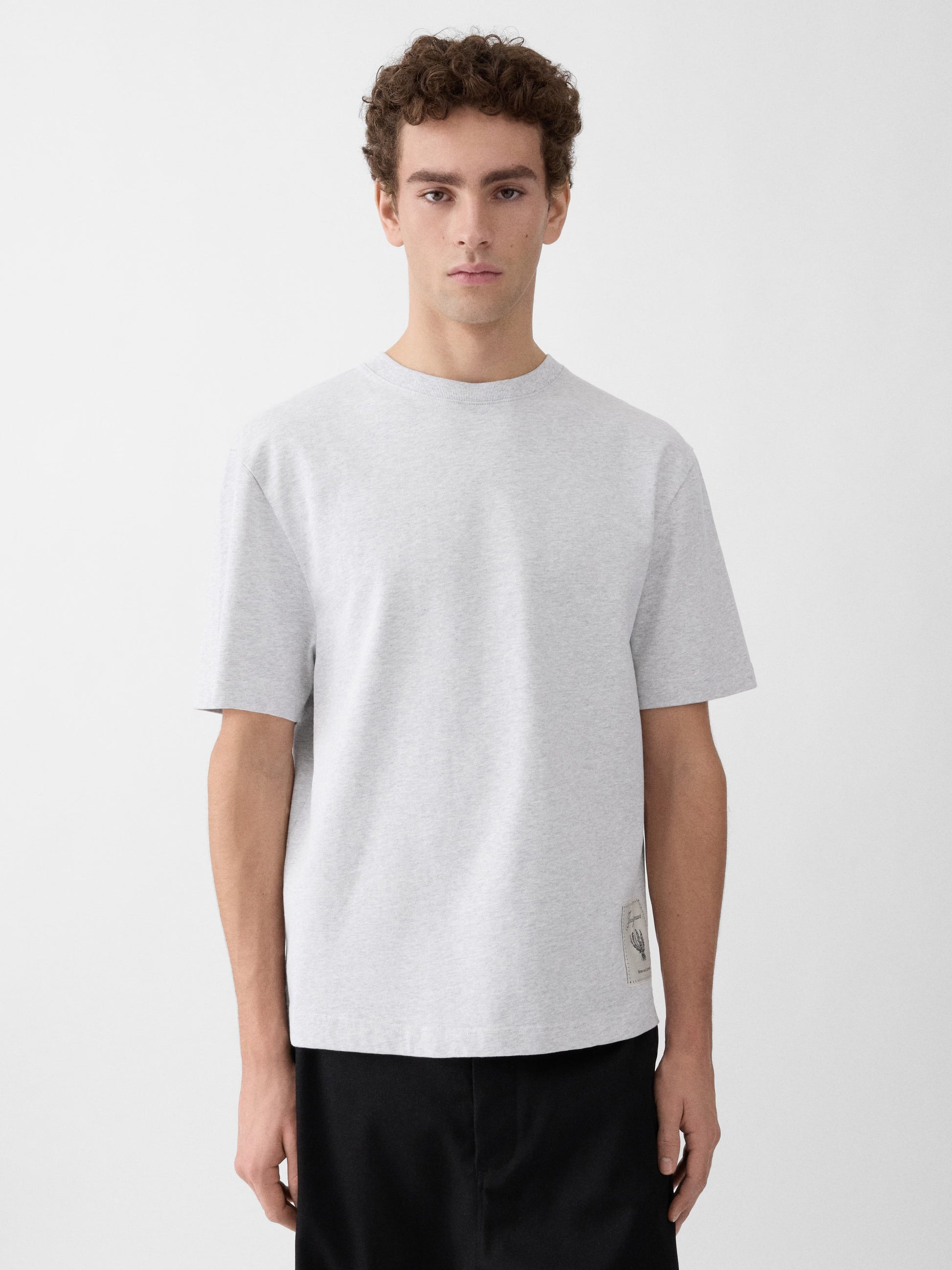 Grey t-shirt with a beige label on a light gray background JACQUEMUS