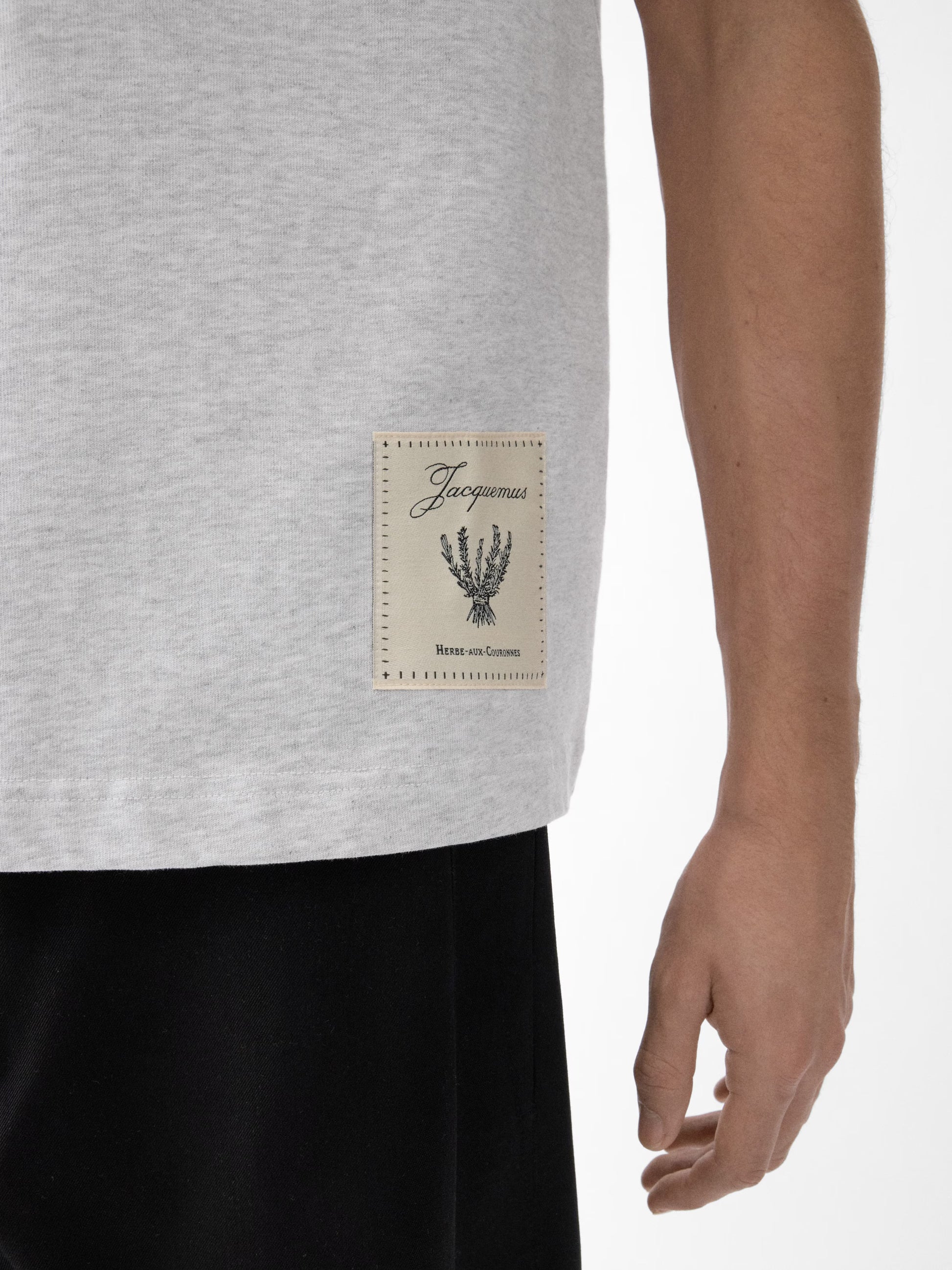 Grey t-shirt with a beige label on a light gray background JACQUEMUS