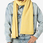 Person wearing a yellow scarf, denim jacket, and jeans on a white background