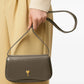 Green handbag with a gold heart emblem on a light beige background ami paris
