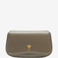 Green handbag with a gold heart emblem on a light beige background ami paris