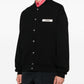 Black varsity jacket with a logo on the chest against a white background