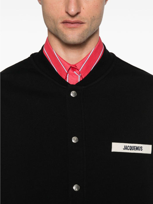 Black varsity jacket with a logo on the chest against a white background
