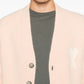Pink cardigan with button details and a bow design on a white background ami paris