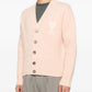 Pink cardigan with button details and a bow design on a white background ami paris
