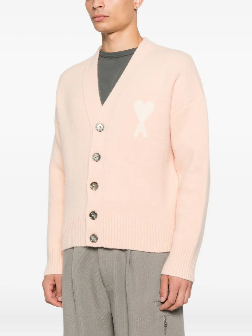 Pink cardigan with button details and a bow design on a white background ami paris