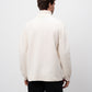 Man wearing a white sweater against a plain background