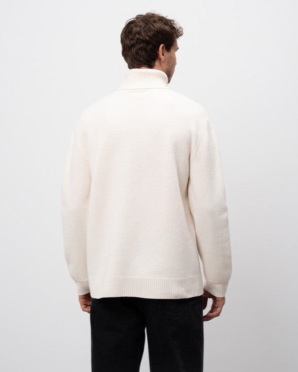 Man wearing a white sweater against a plain background