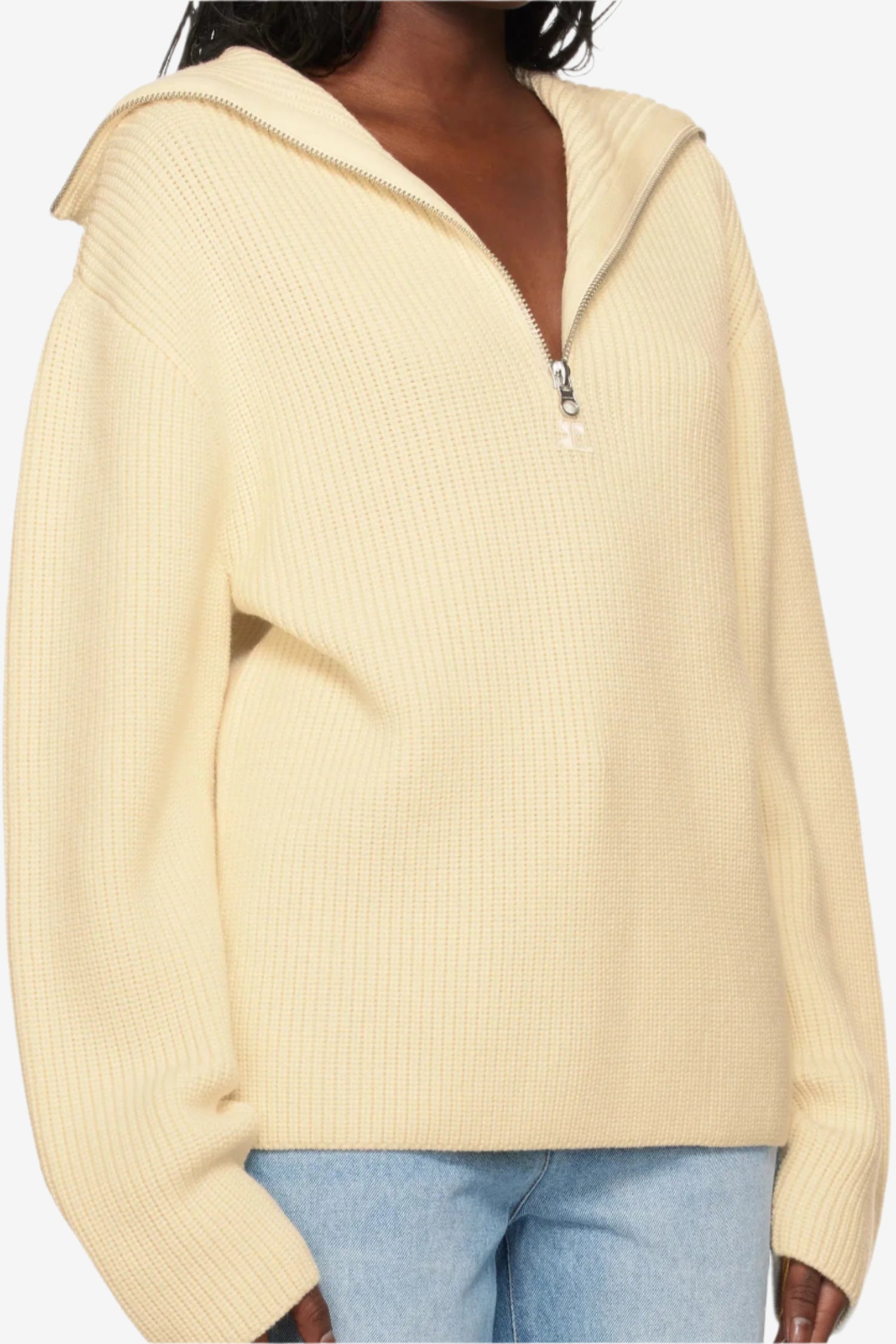 Woman wearing a beige hoodie with a zipper, standing against a neutral background