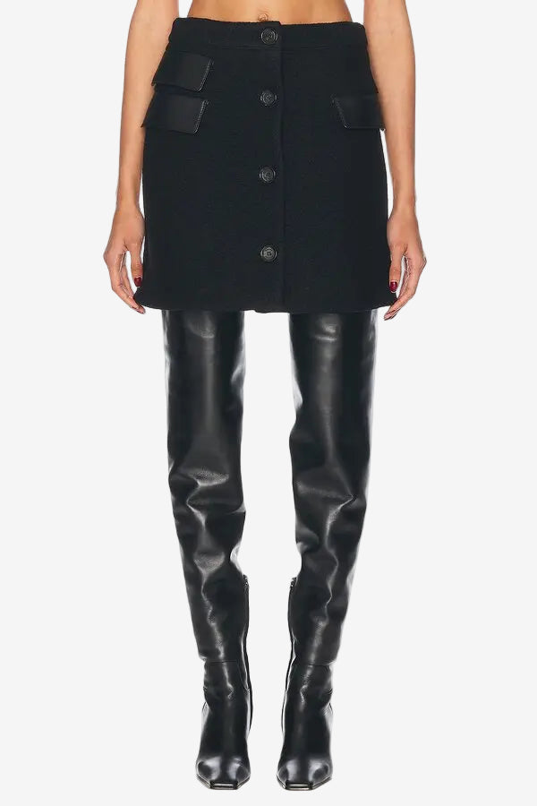 Person wearing a black button-up skirt and black leggings on a white background