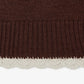 A dark brown knit sweater with a small white embroidered heart logo on the left chest, displayed flat against a light gray background.
