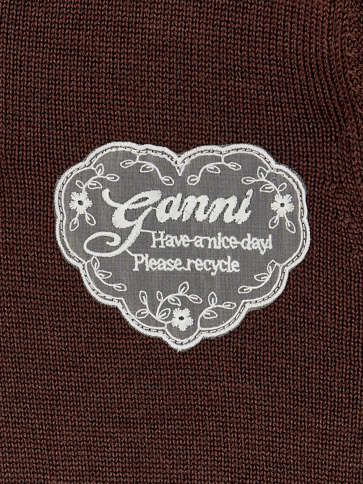 A dark brown knit sweater with a small white embroidered heart logo on the left chest, displayed flat against a light gray background.