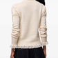 A light beige knit turtleneck sweater with long sleeves and a sheer ruffled hem, displayed against a plain white background.