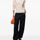 A light beige knit turtleneck sweater with long sleeves and a sheer ruffled hem, displayed against a plain white background.