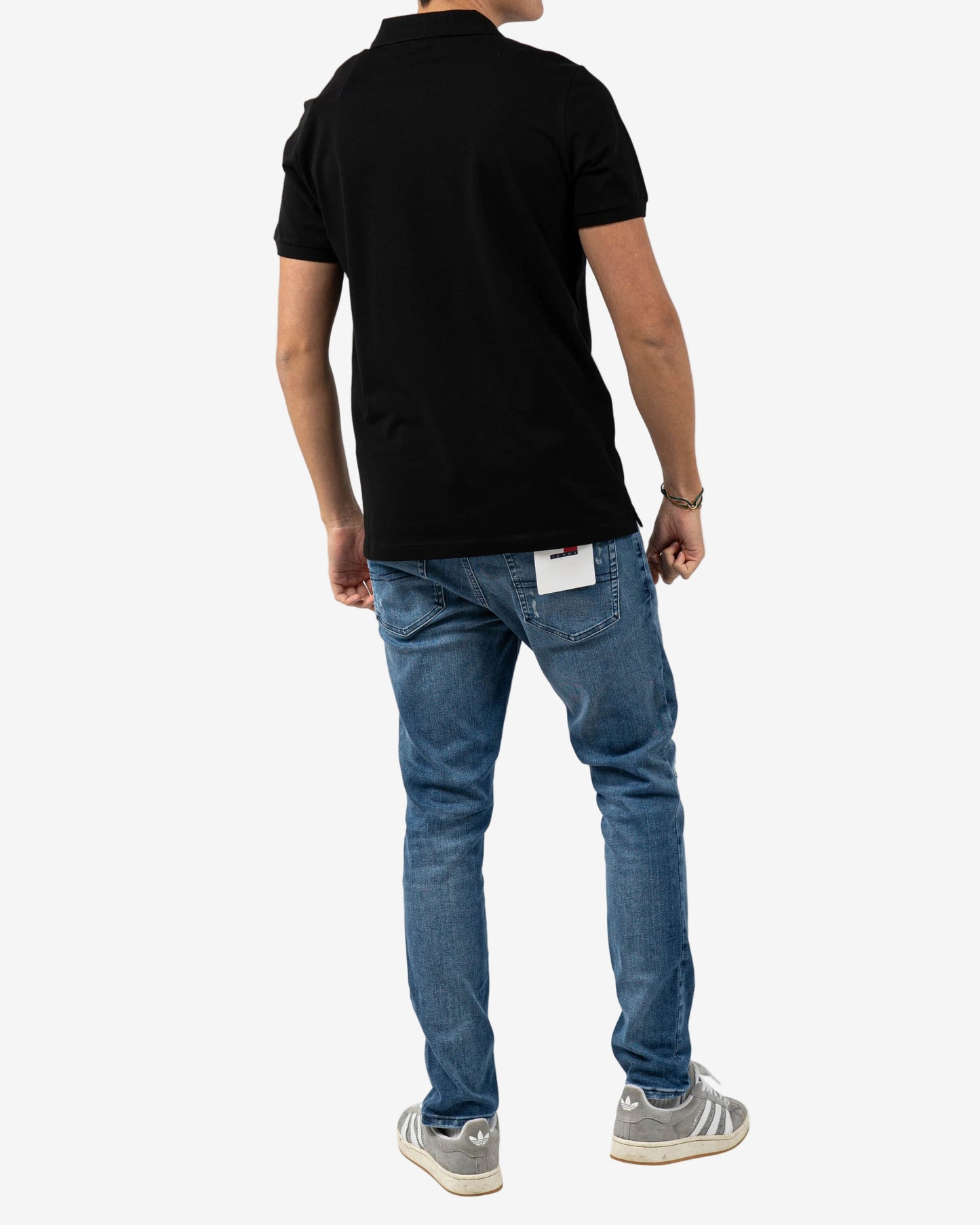 Person wearing a black polo shirt and blue jeans on a white background