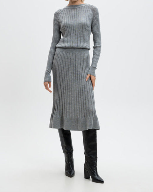Woman wearing a gray ribbed sweater and skirt set with black knee-high boots on a white background