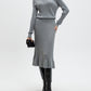 Woman wearing a gray ribbed sweater and skirt set with black knee-high boots on a white background