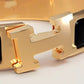Gold bracelet with black band on a light gray background