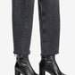 Black leather ankle boots worn with black jeans on a white background