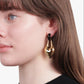 Woman wearing gold hoop earrings with a neutral background