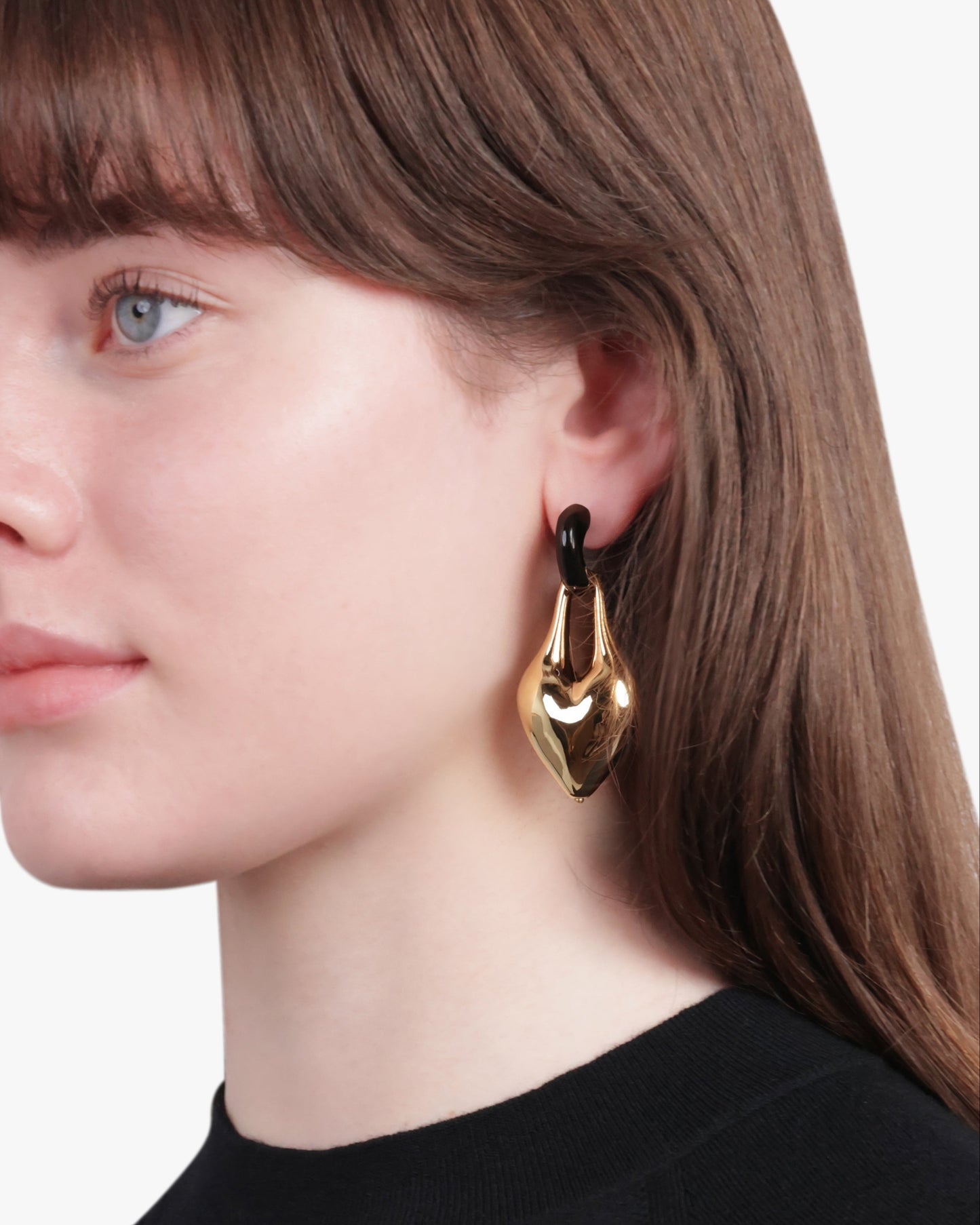 Woman wearing gold hoop earrings with a neutral background