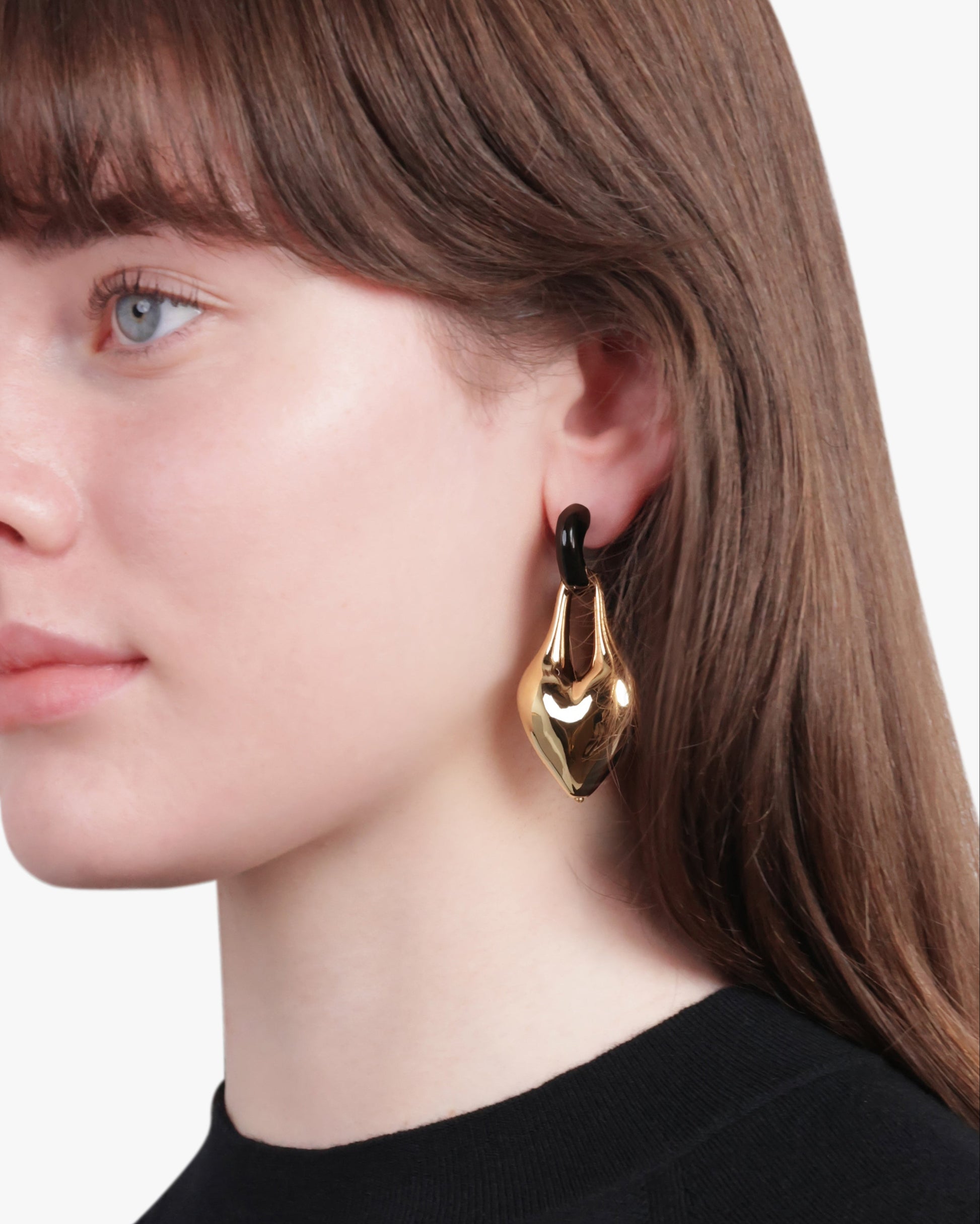 Woman wearing gold hoop earrings with a neutral background