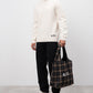 Man holding a plaid bag with 'A.P.C.' branding against a white background