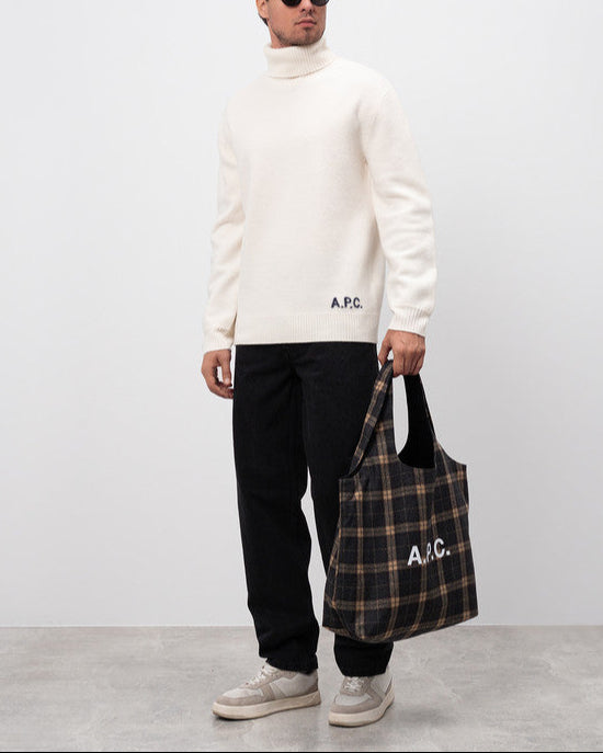 Man holding a plaid bag with 'A.P.C.' branding against a white background