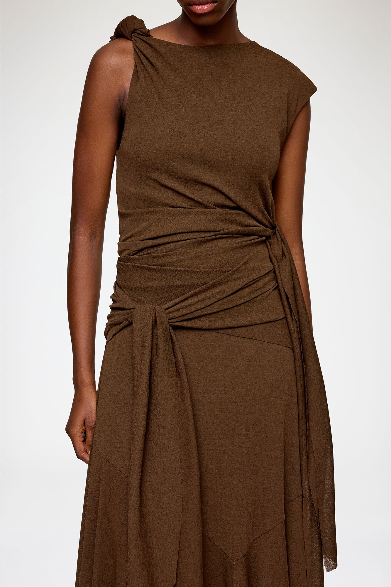 Brown sleeveless dress with a draped design on a white background