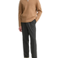 Man wearing a beige sweater and gray pants on a white background