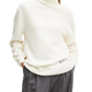 Woman wearing a white turtleneck sweater with a brand logo on a white background