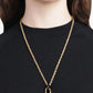 Gold necklace with a heart pendant worn by a person on a black background