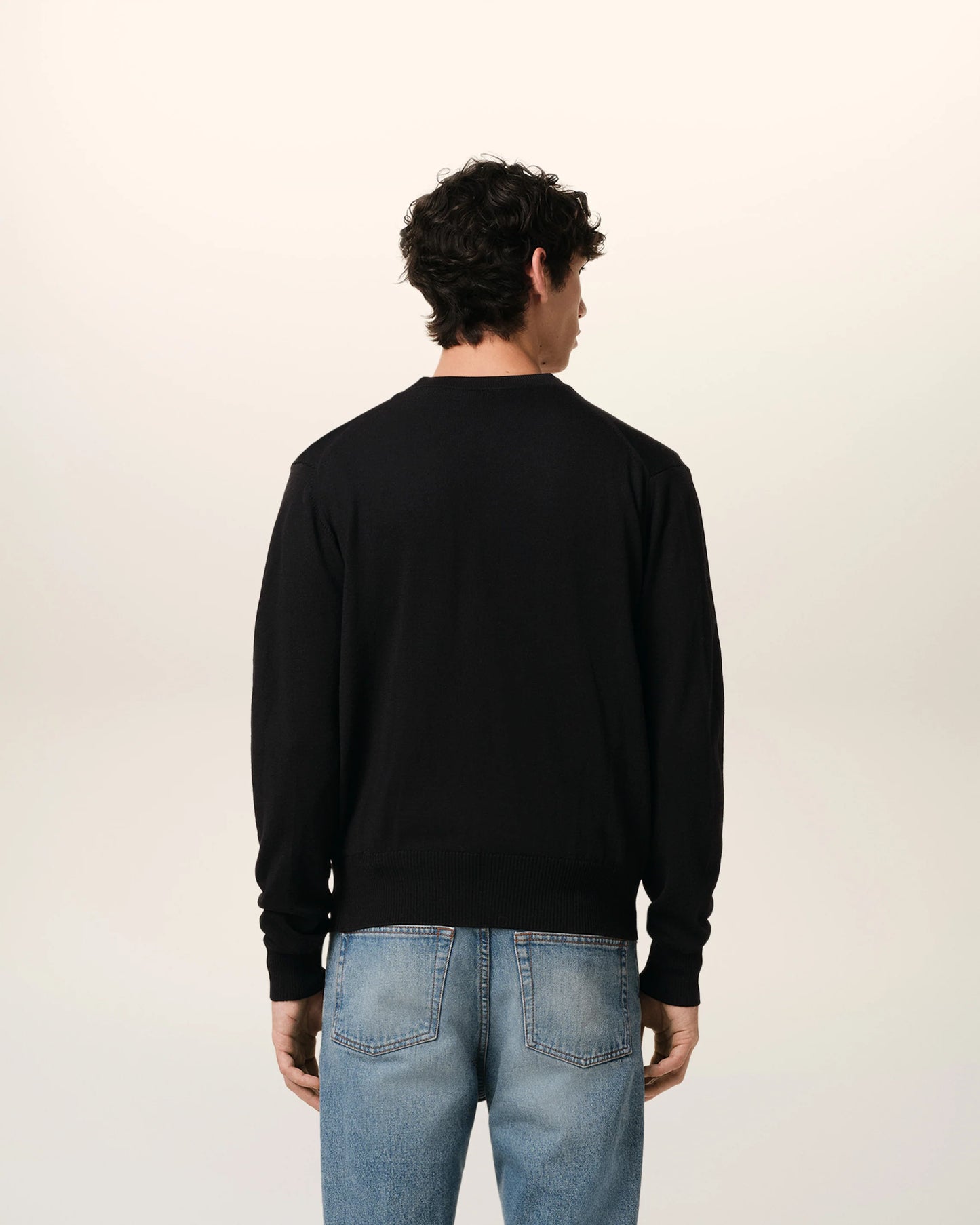 Black cardigan with a small red heart emblem on a white background
