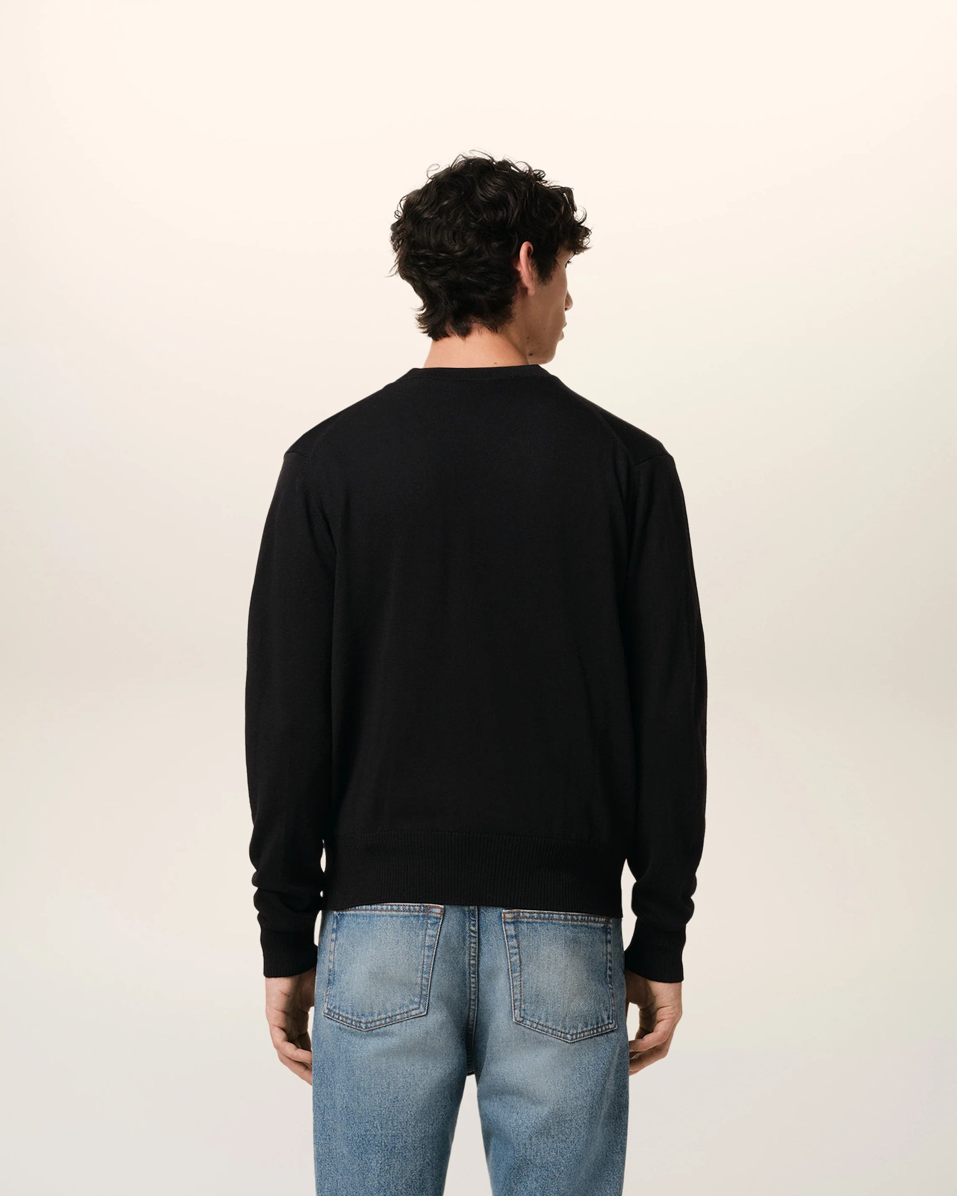 Black cardigan with a small red heart emblem on a white background