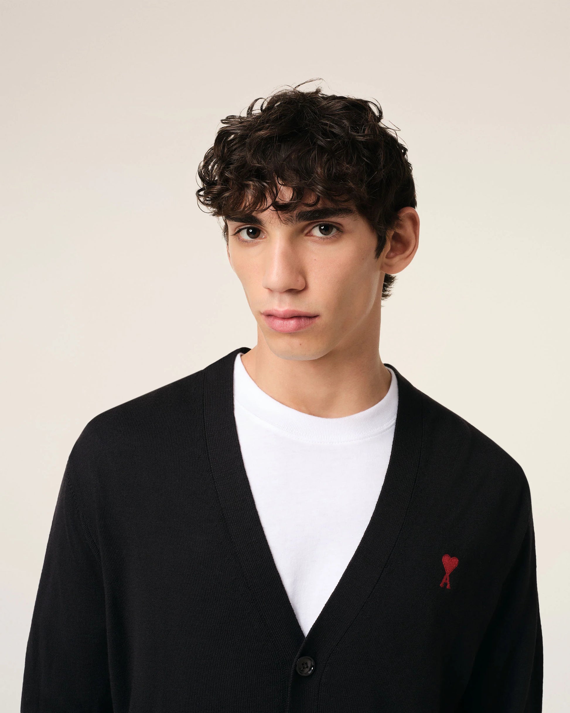 Black cardigan with a small red heart emblem on a white background