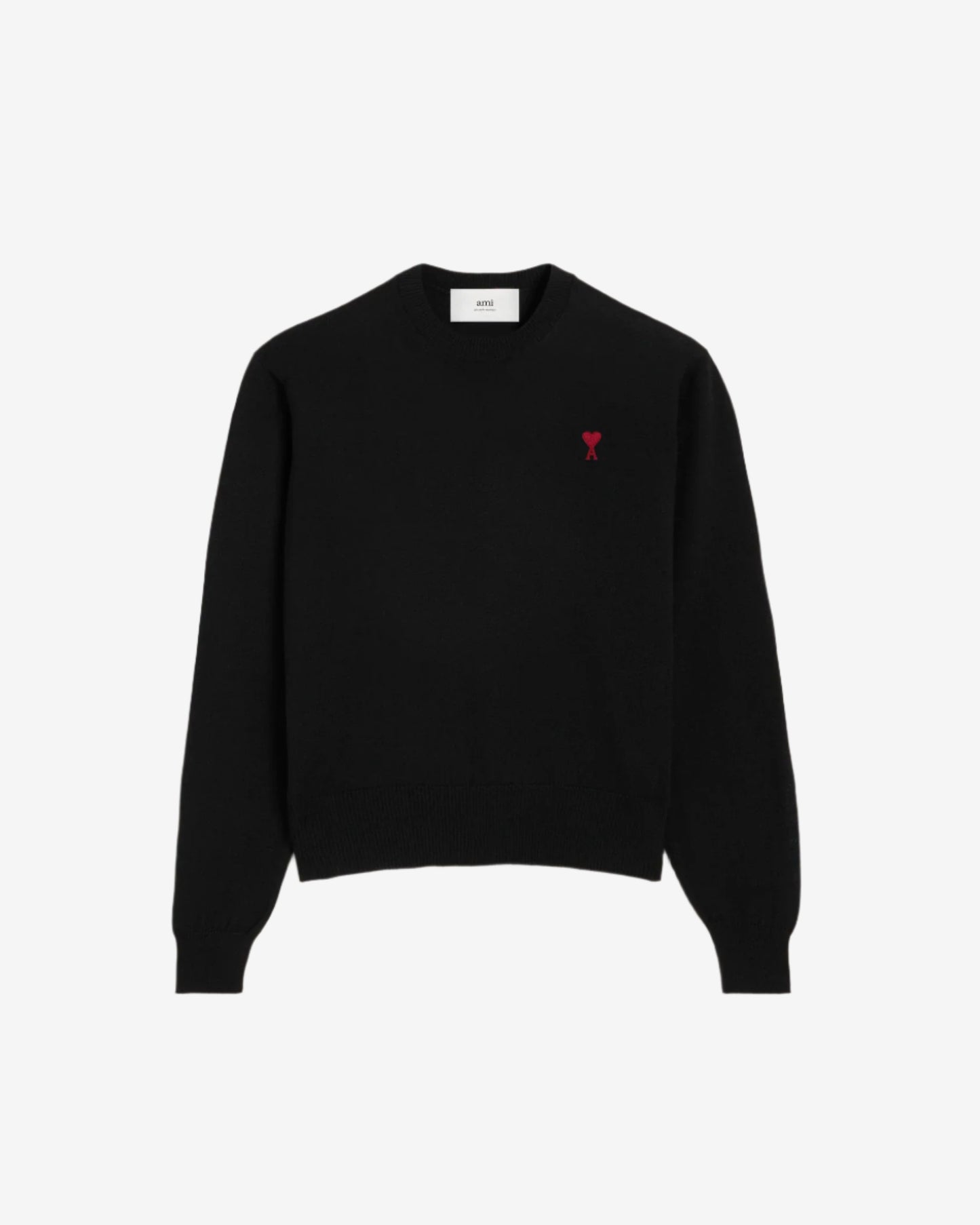 Black sweater with a small red heart emblem on a beige background