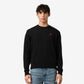 Black sweater with a small red heart emblem on a beige background