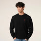Black sweater with a small red heart emblem on a beige background
