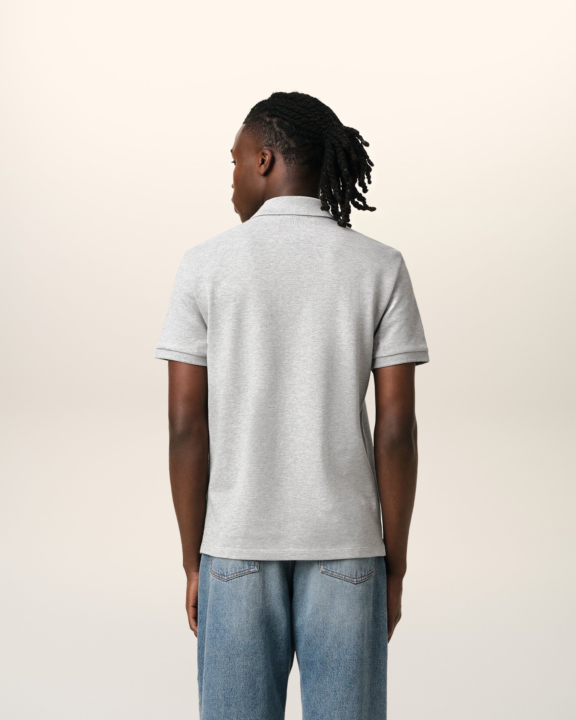 Gray polo shirt with a small red logo on a beige background