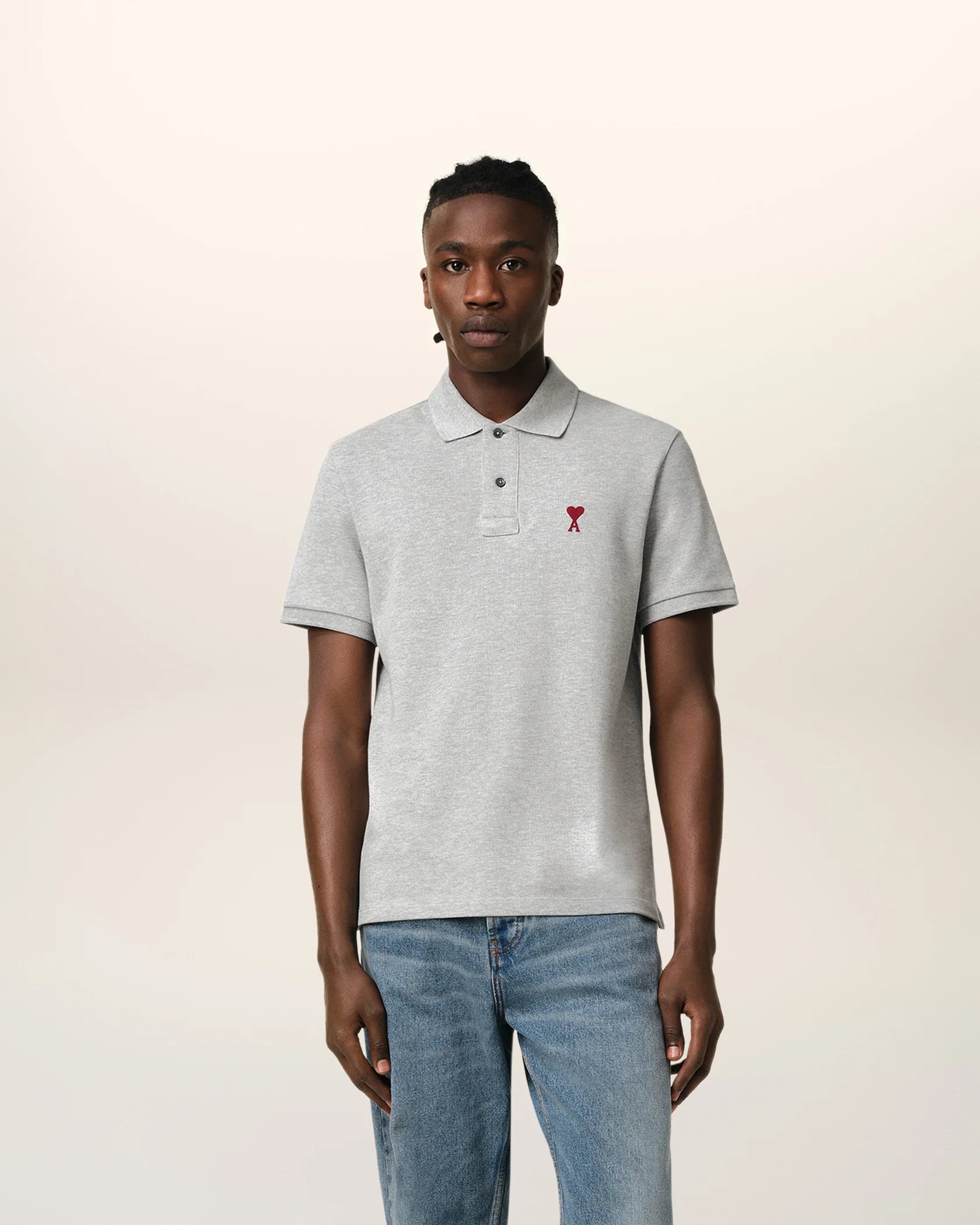 Gray polo shirt with a small red logo on a beige background