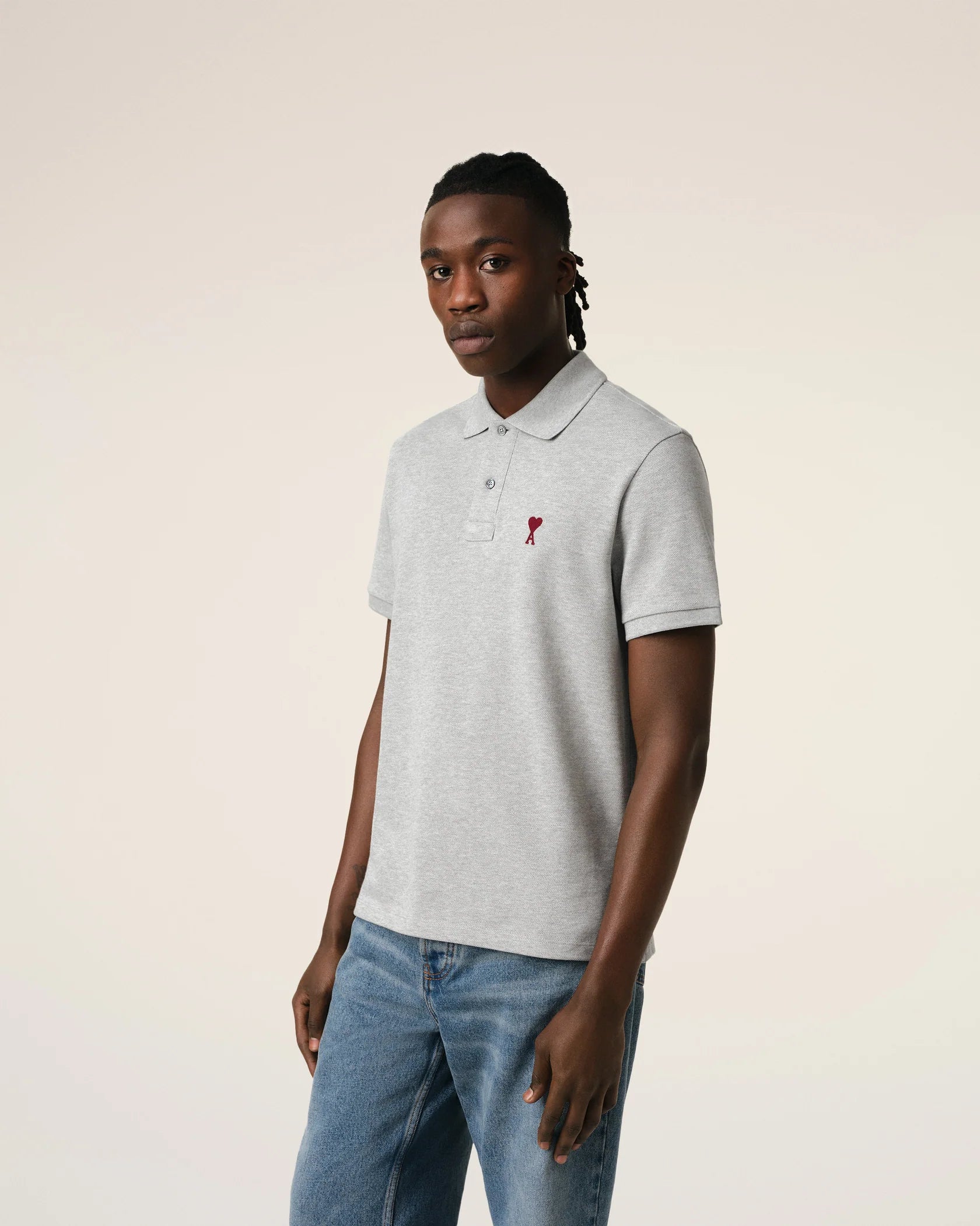 Gray polo shirt with a small red logo on a beige background