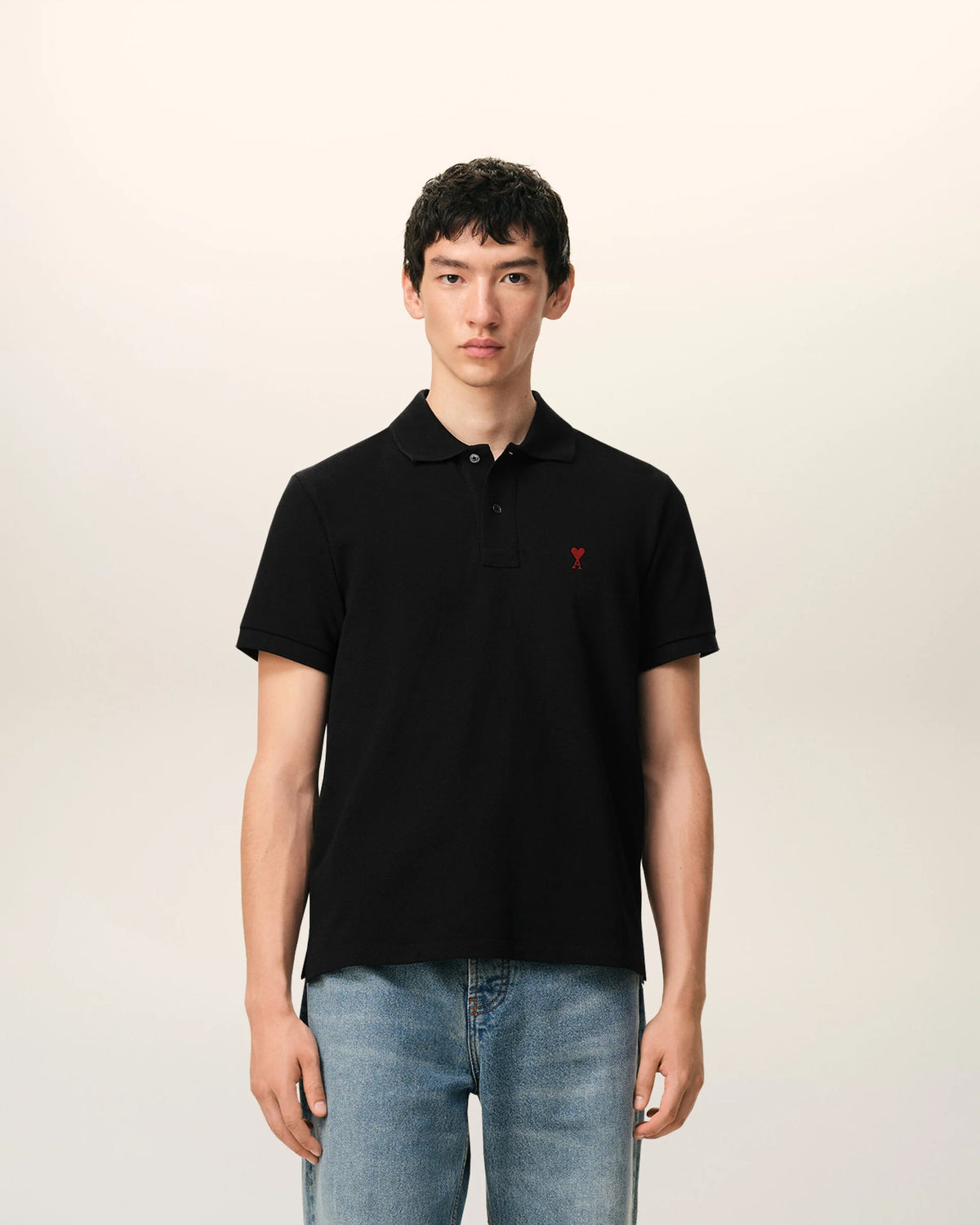 Black polo shirt with a red heart emblem on a beige background ami paris