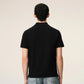 Black polo shirt with a red heart emblem on a beige background ami paris