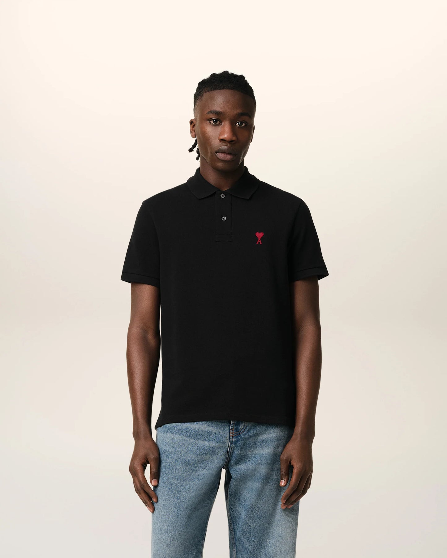 Black polo shirt with a small red logo on a beige background